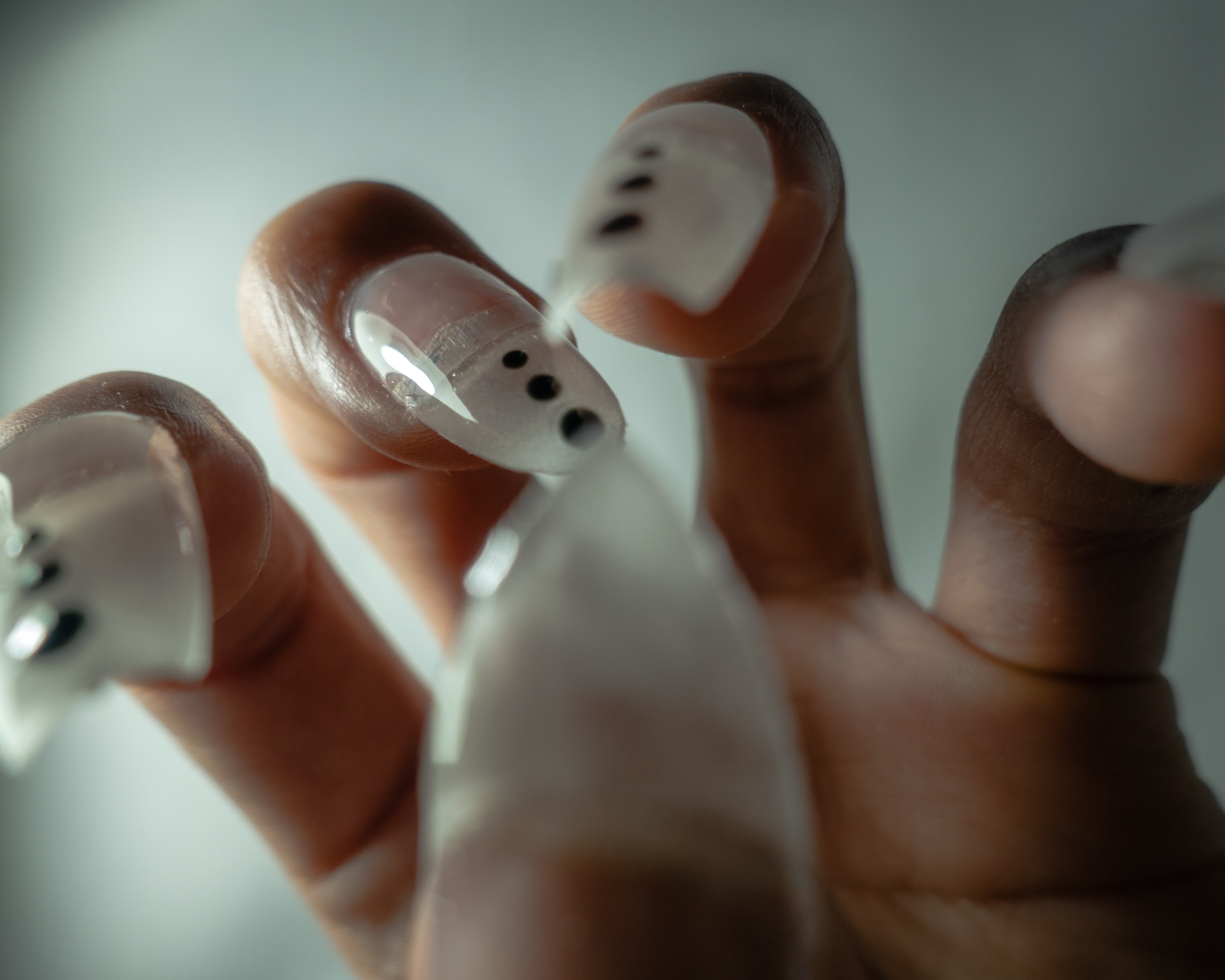 透明なクリアネイルに黒いドットが並んだデザイン。未来的な形状。チップによる長さだし。超高光沢で、前衛的なネイルアート。